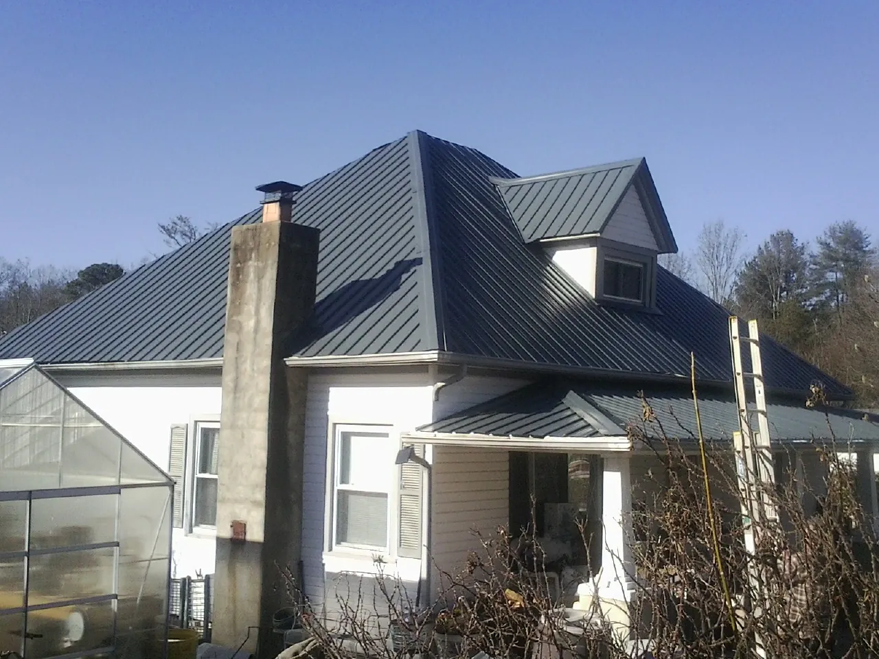 Dark blue standing seam metal roof on a white farmhouse with dormer — Slate & Tile Roof Repair by Roofing Brothers in Adelphi