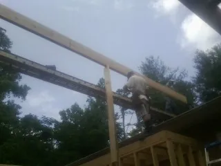 Carpenter setting a ridge beam over a new addition frame — Ice Dam Removal by Roofing Brothers in Adelphi