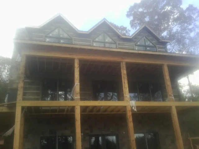 Dormers and porch framing on a large log home under construction — Roof Coating work by our crew in Adelphi