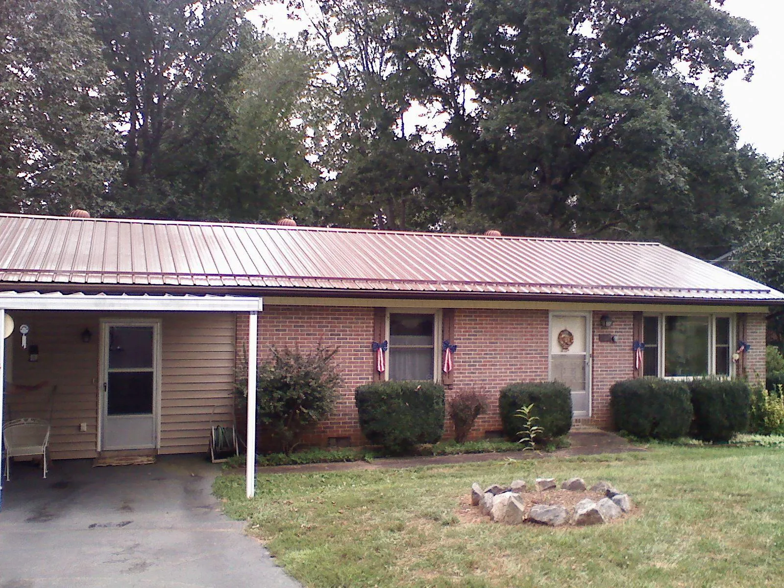 Bronze metal roof and carport on a brick ranch home — Roof Repair work by our crew in Adelphi