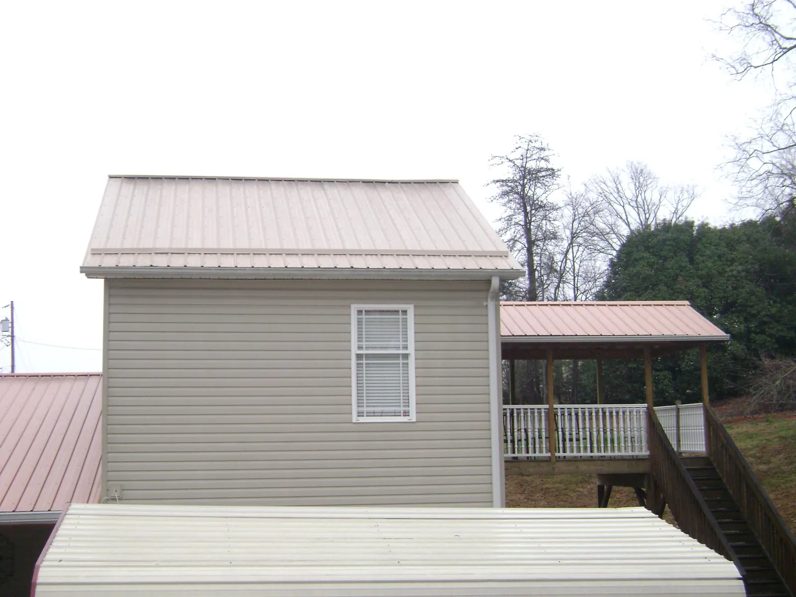 Tan metal roofs on a two story addition and attached porch, from a Roof Replacement job in Adelphi