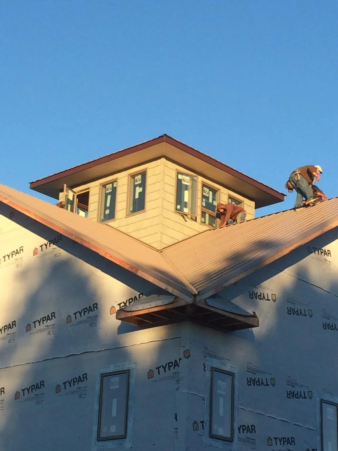 Roofers working around a rooftop cupola on a new metal roof at sunset — Roof Waterproofing in Adelphi by Roofing Brothers